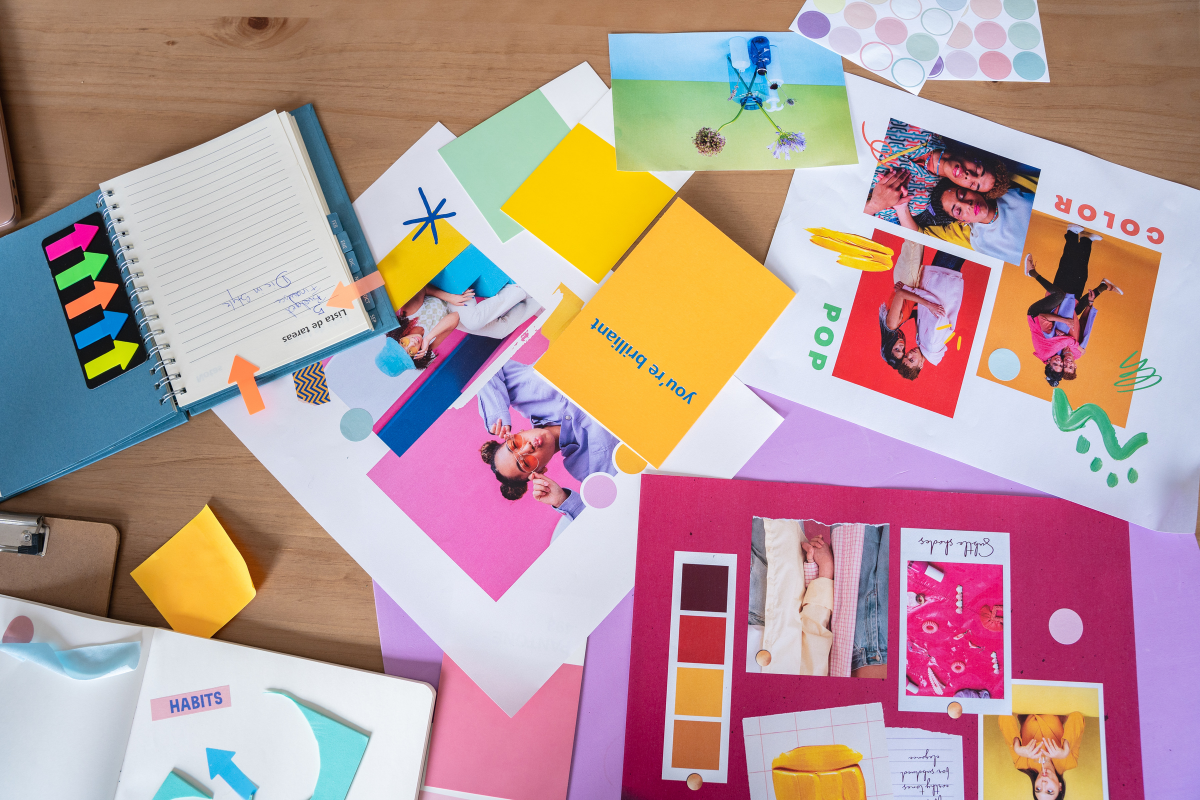 Table de travail avec des moodboards colorés, des images, des notes et des palettes de couleurs pour créer une identité visuelle.